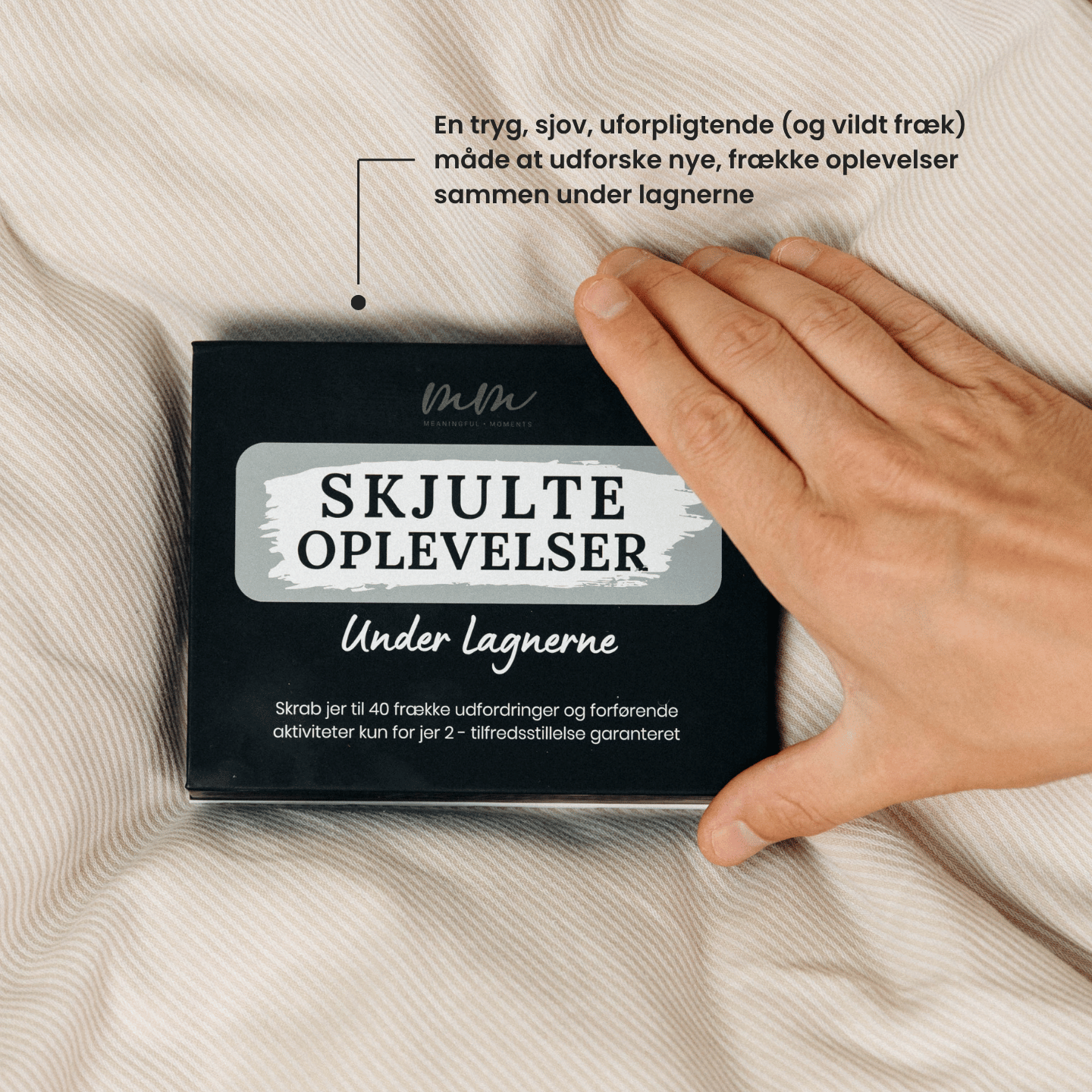 Hånd der rører ved SkjulteOplevelser™ – Under Lagnerne spillet, en fræk og sjov måde for par at udforske nye oplevelser sammen i soveværelset.